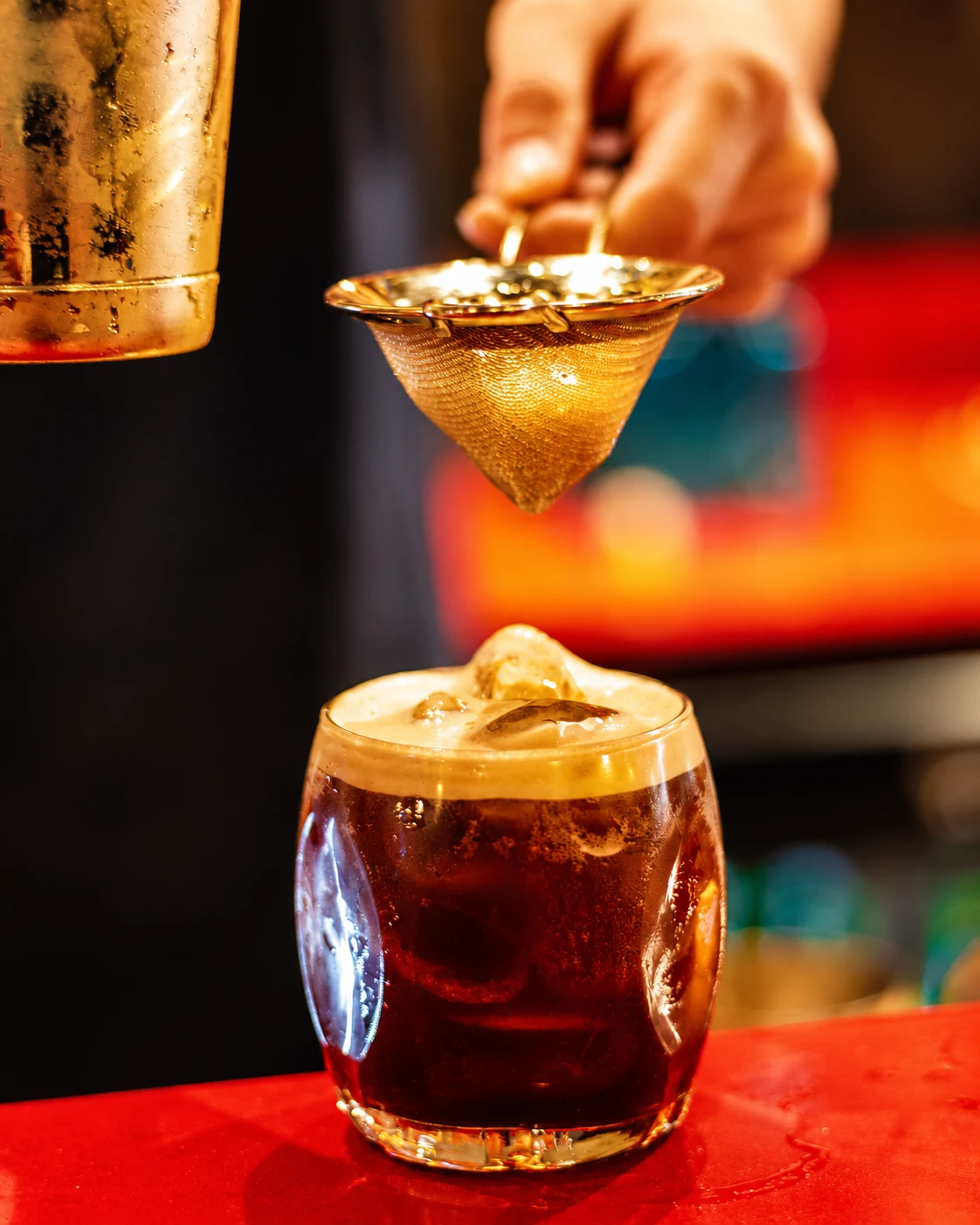 Un cocktail ambré préparé à la lumière chaleureuse du bar